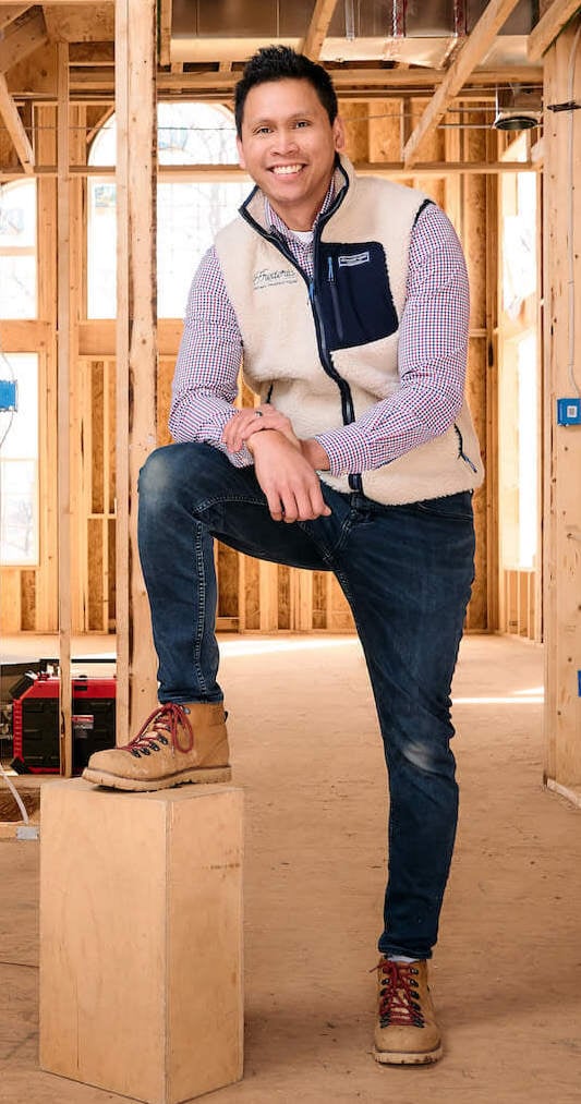 A home inspector smiling and posing in a new construction house.