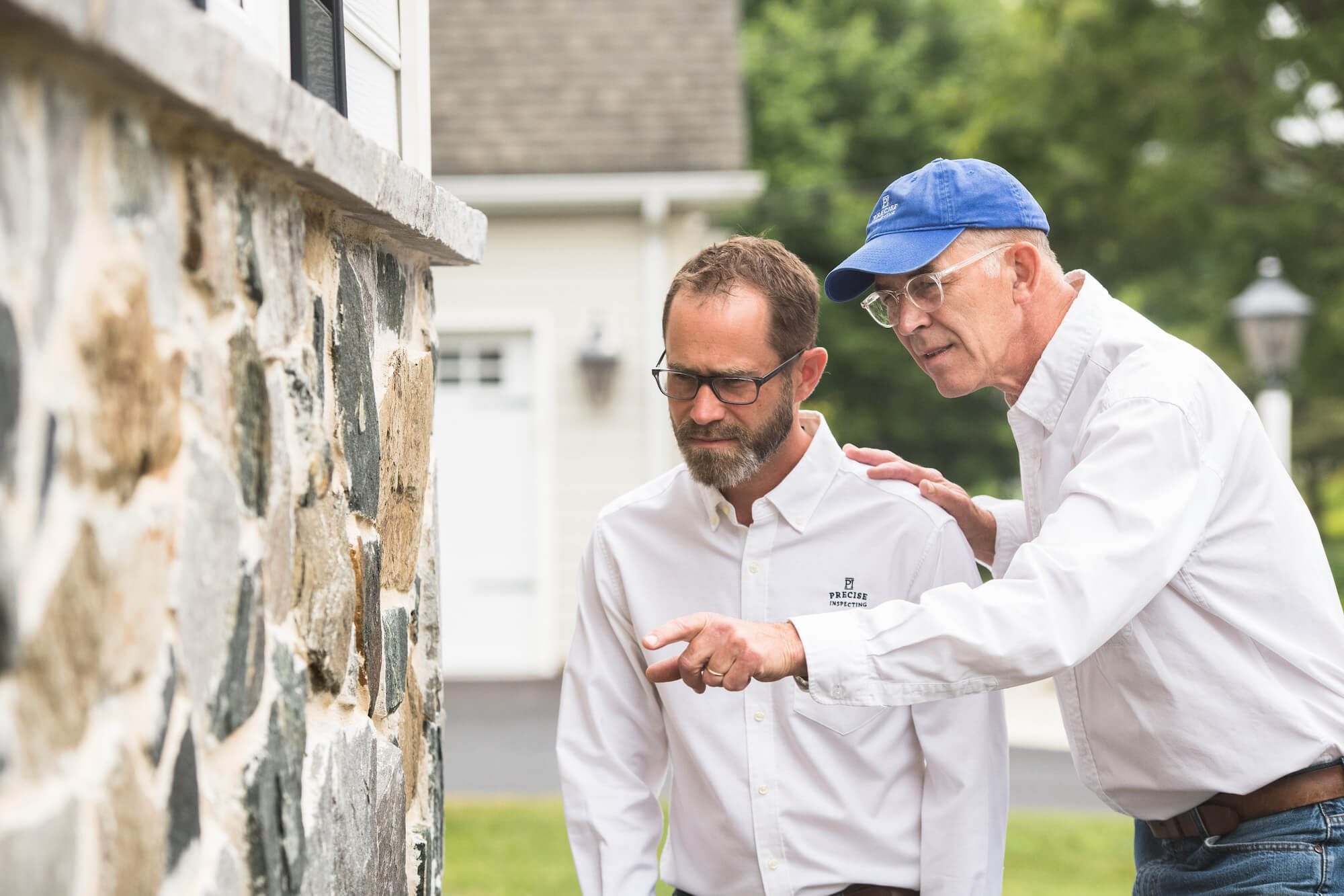 A home inspector showing a homebuyer a defect on an outer wall. 